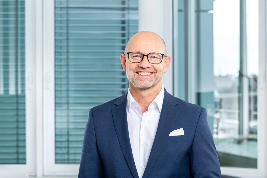 middle aged man in suit inside office with building in background